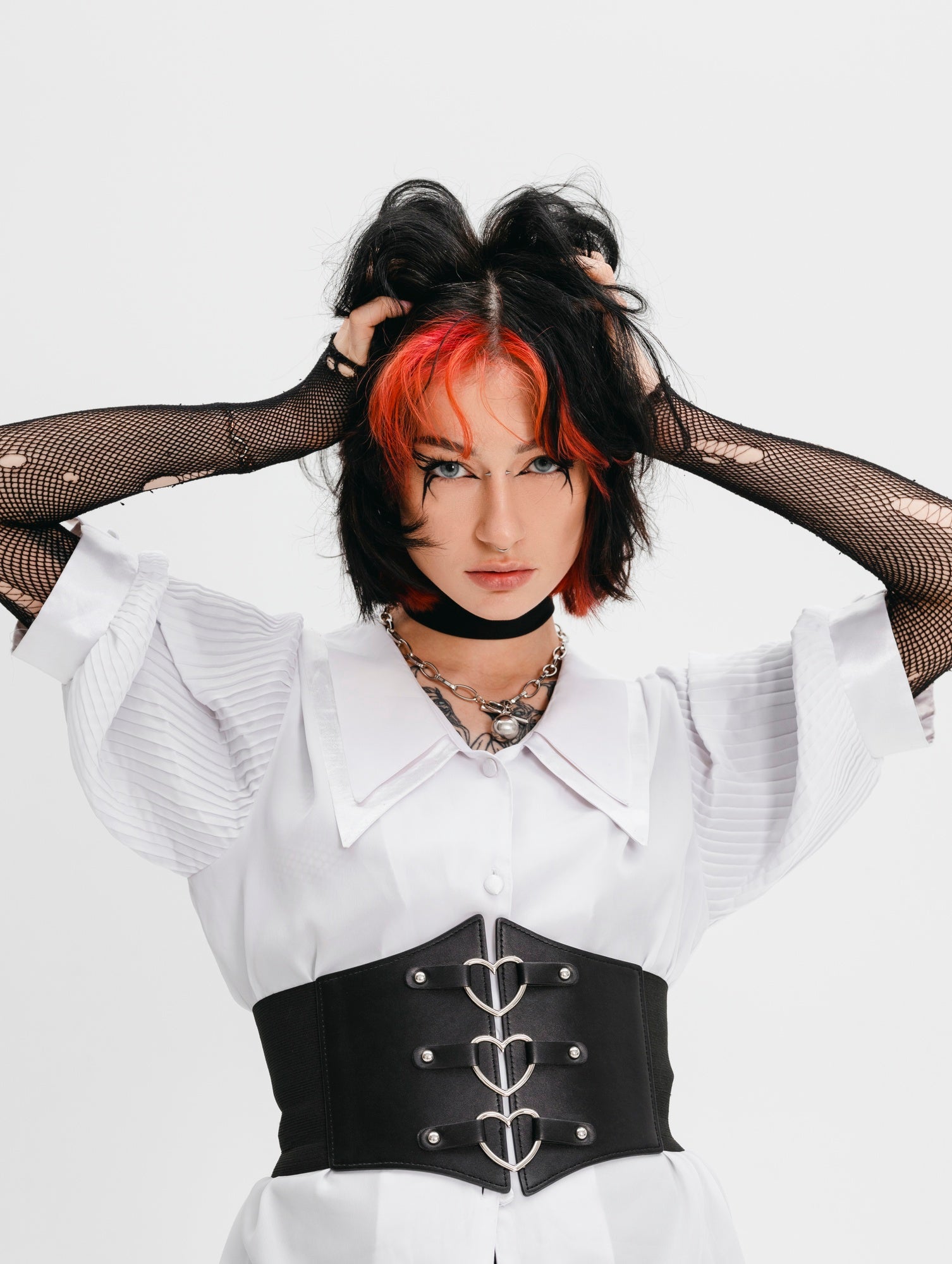 Person wearing a white blouse with a black corset belt against a white background
