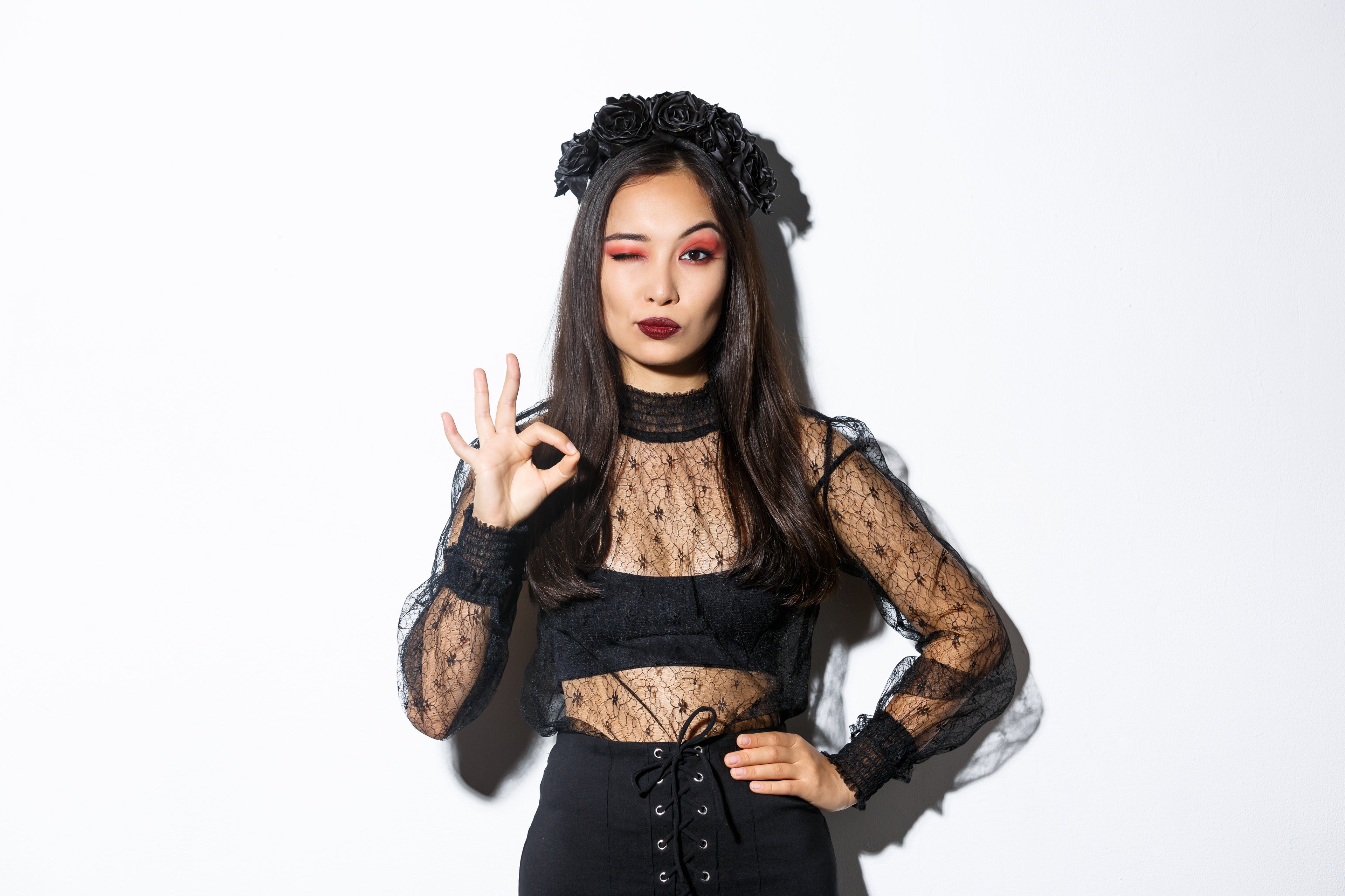 Woman wearing a black lace outfit with a white background